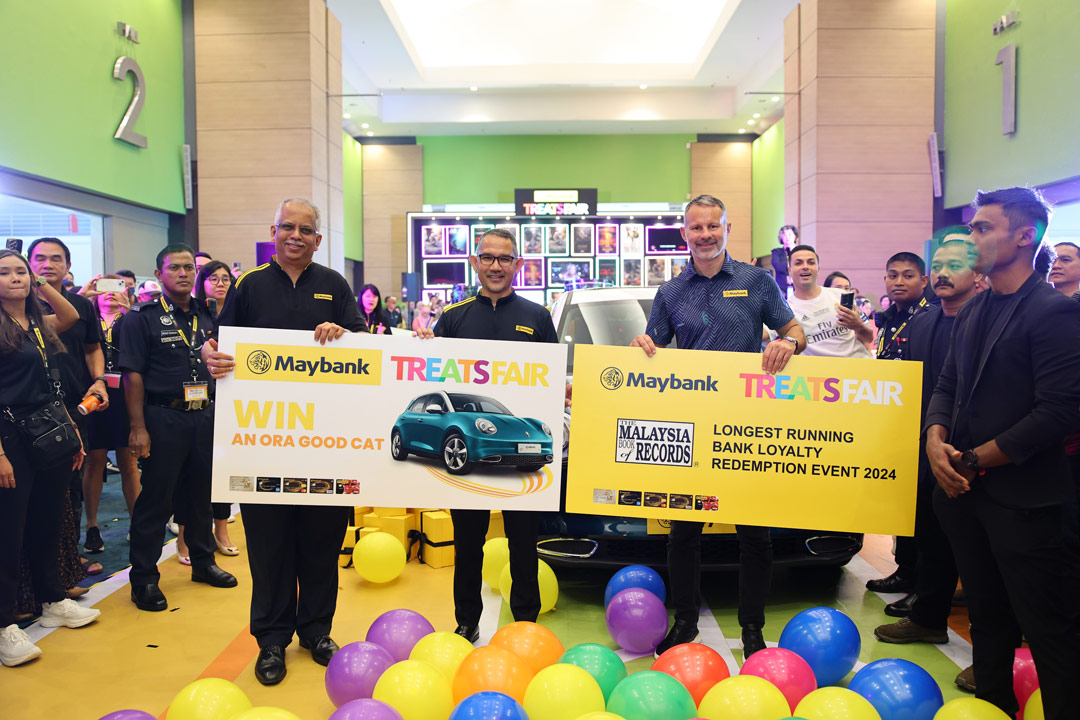 B. Ravintharan (Head of Cards), Sued Ahmad Taufik Albar (Group CEO of Community Financial Services) and Football Legend – Ryan Giggs holding a “Win An Ora Good Cat” and “Malaysia Book of Records – Longest Running Bank Loyalty Redemption Event 2024” placards.